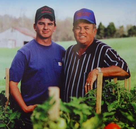 Brandon & Hubert Williams standing in  row crop of tomatoes 